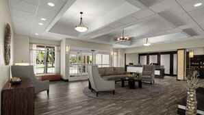 A spacious lobby with a large sofa, armchairs, and a coffee table. There are ceiling lights and a decorative vase on a table. - Homewood Suites by Hilton Bakersfield (Bakersfield)