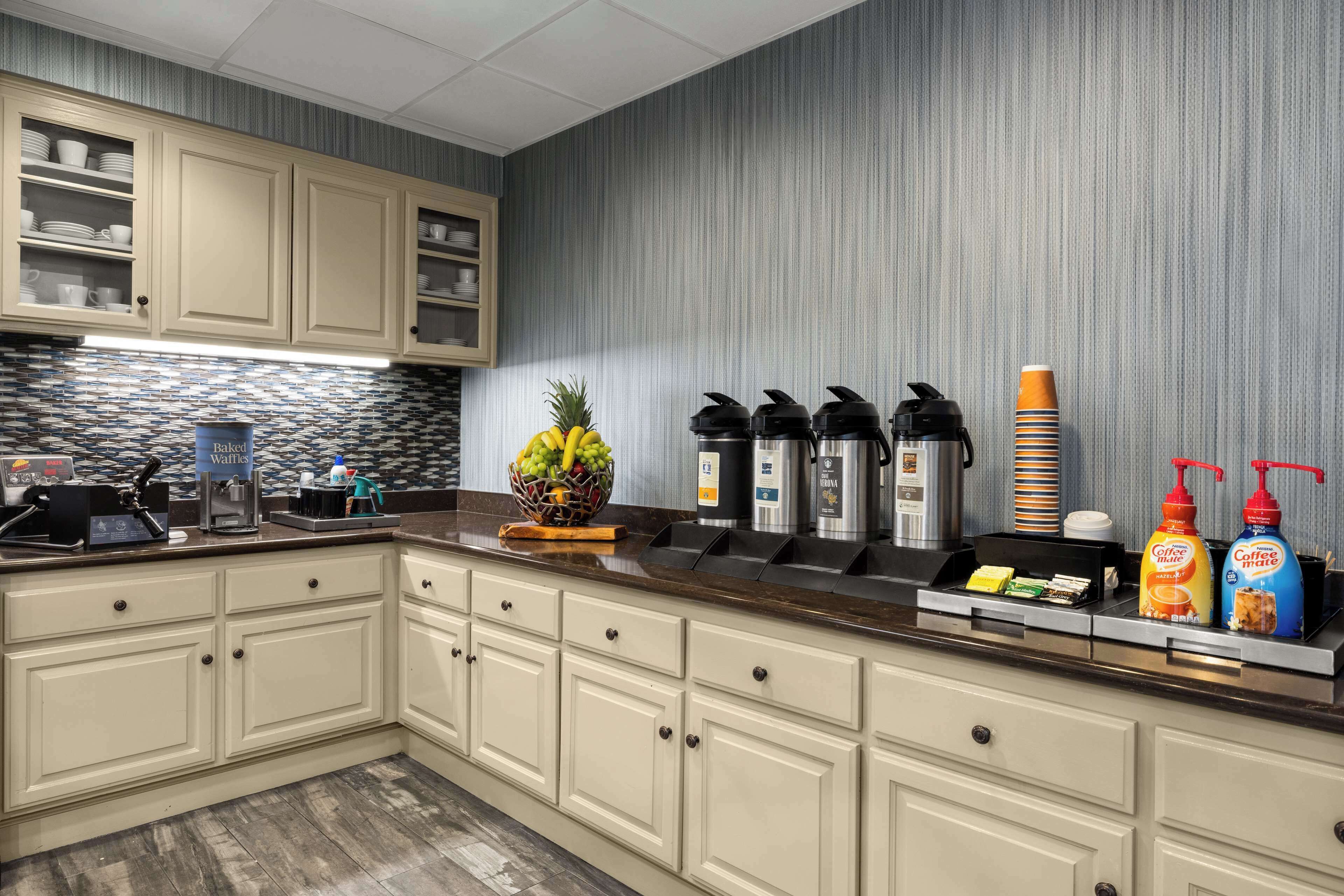 A modern kitchen with a breakfast bar, a coffee station, and a fruit basket.