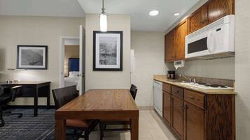 A modern kitchen with wooden cabinets, a built-in microwave, and a dining area with a table and chairs.