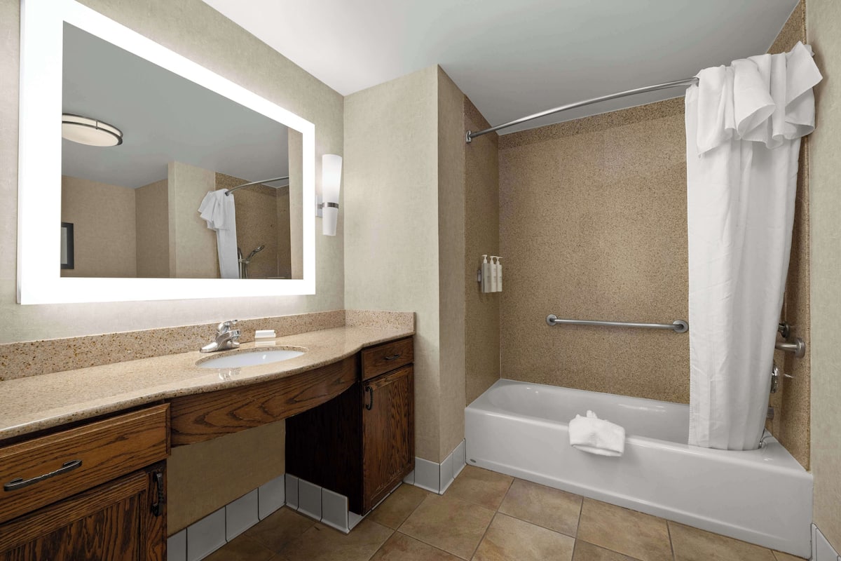 Un baño con lavamanos, espejo, tocador, ducha y bañera.