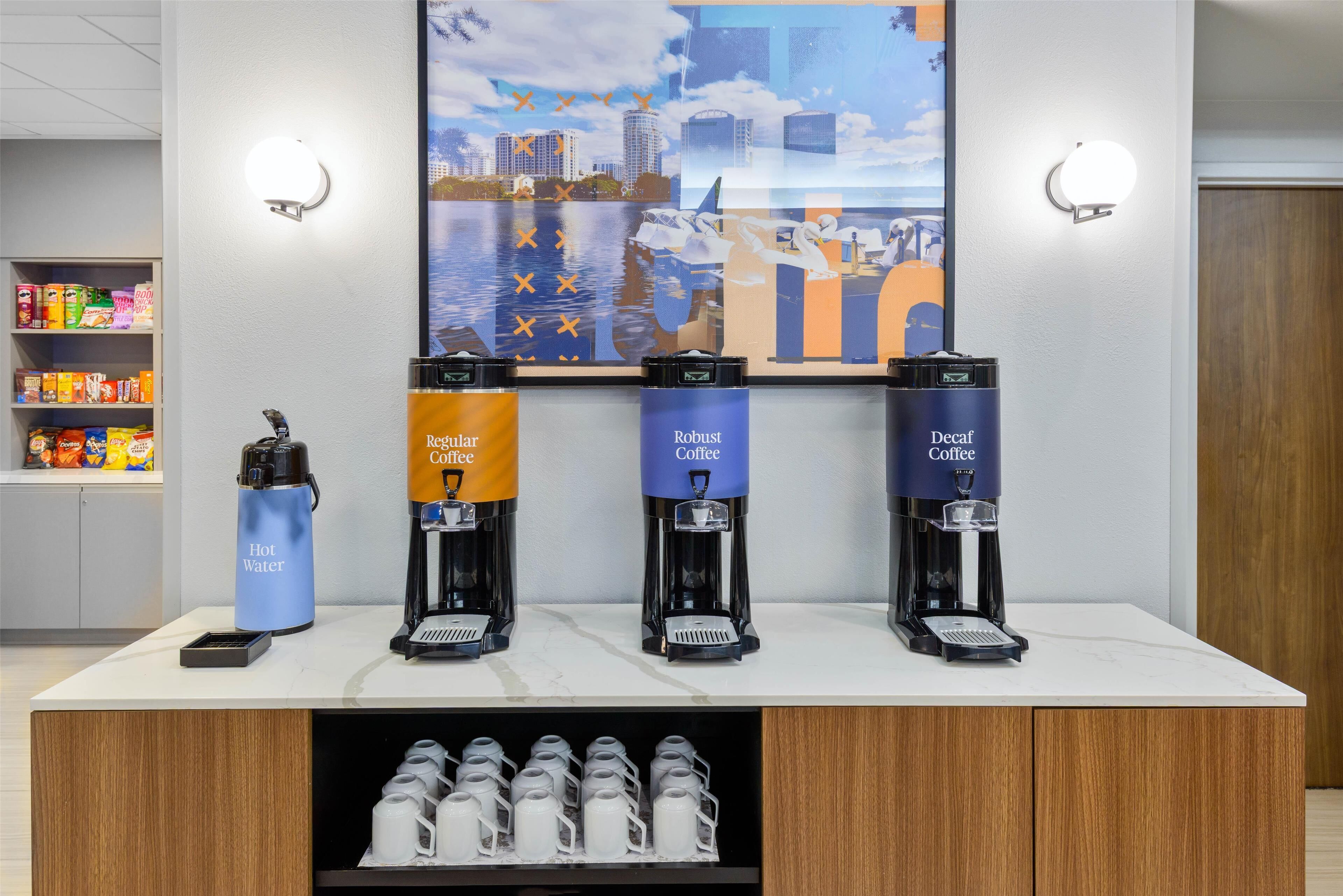 A coffee station with three coffee dispensers labeled "Regular Coffee," "Robust Coffee," and "Decaf Coffee." A hot water dispenser and a phone are also visible.