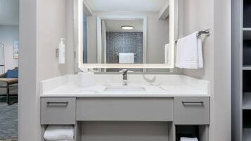 A modern bathroom with a white sink, two towel racks, and a mirror.