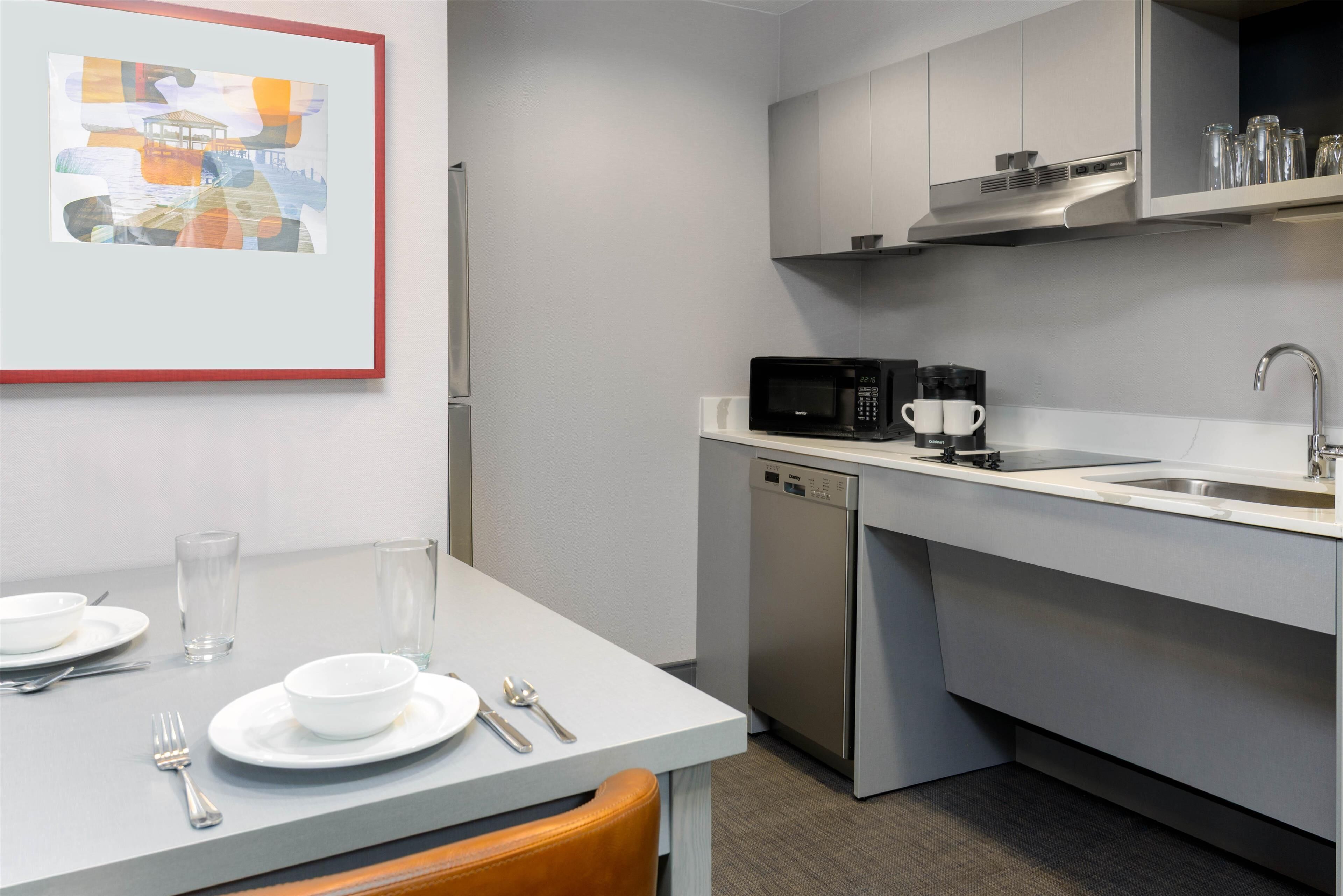 Una cocina moderna con una mesa de comedor lista para dos personas, un microondas y un lavavajillas.
