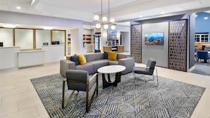 Eine moderne Lobby mit einer Eckcouch, einem runden Couchtisch und einer Sitzecke mit einem gemusterten Teppich.