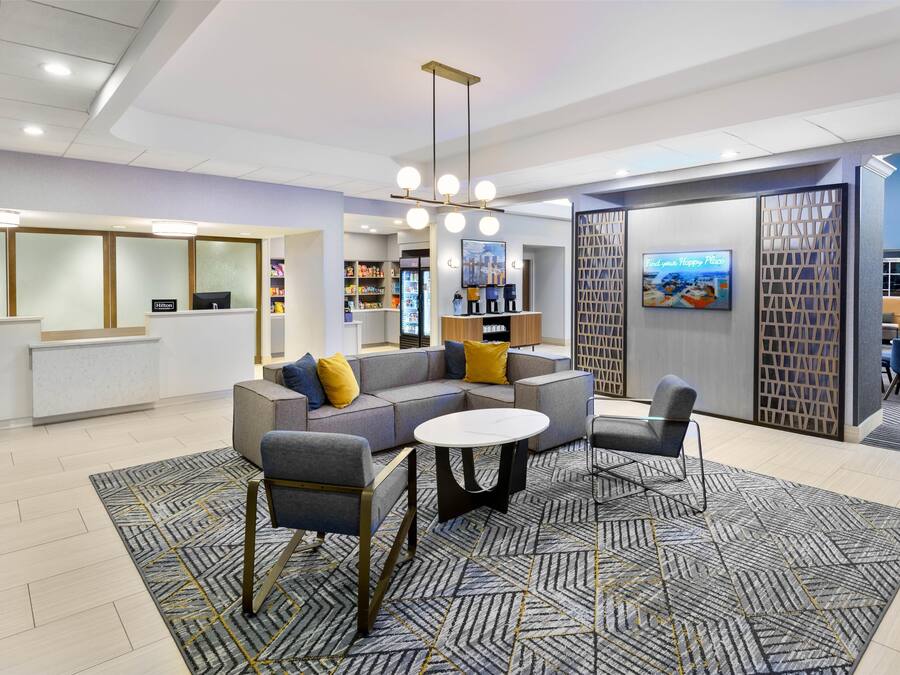 A modern lobby with a sectional sofa, a round coffee table, and a seating area with a patterned rug.