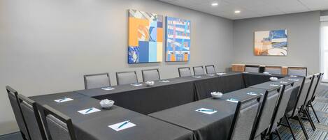 A conference room with a long table, chairs, and artwork on the walls.