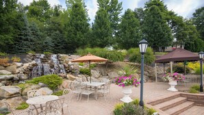 A patio area with outdoor furniture, a waterfall, and a gazebo.