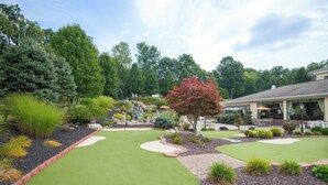 A well-maintained garden with a putting green, a variety of shrubs, and a small waterfall feature. - Holiday Inn Express & Suites Sharon-Hermitage by IHG (West Middlesex)