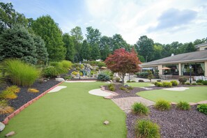 A well-maintained garden with a putting green, a variety of shrubs, and a small waterfall feature. - Holiday Inn Express & Suites Sharon-Hermitage by IHG (West Middlesex)