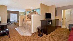 A hotel room with a dining area, a TV, a small table, and a sofa.