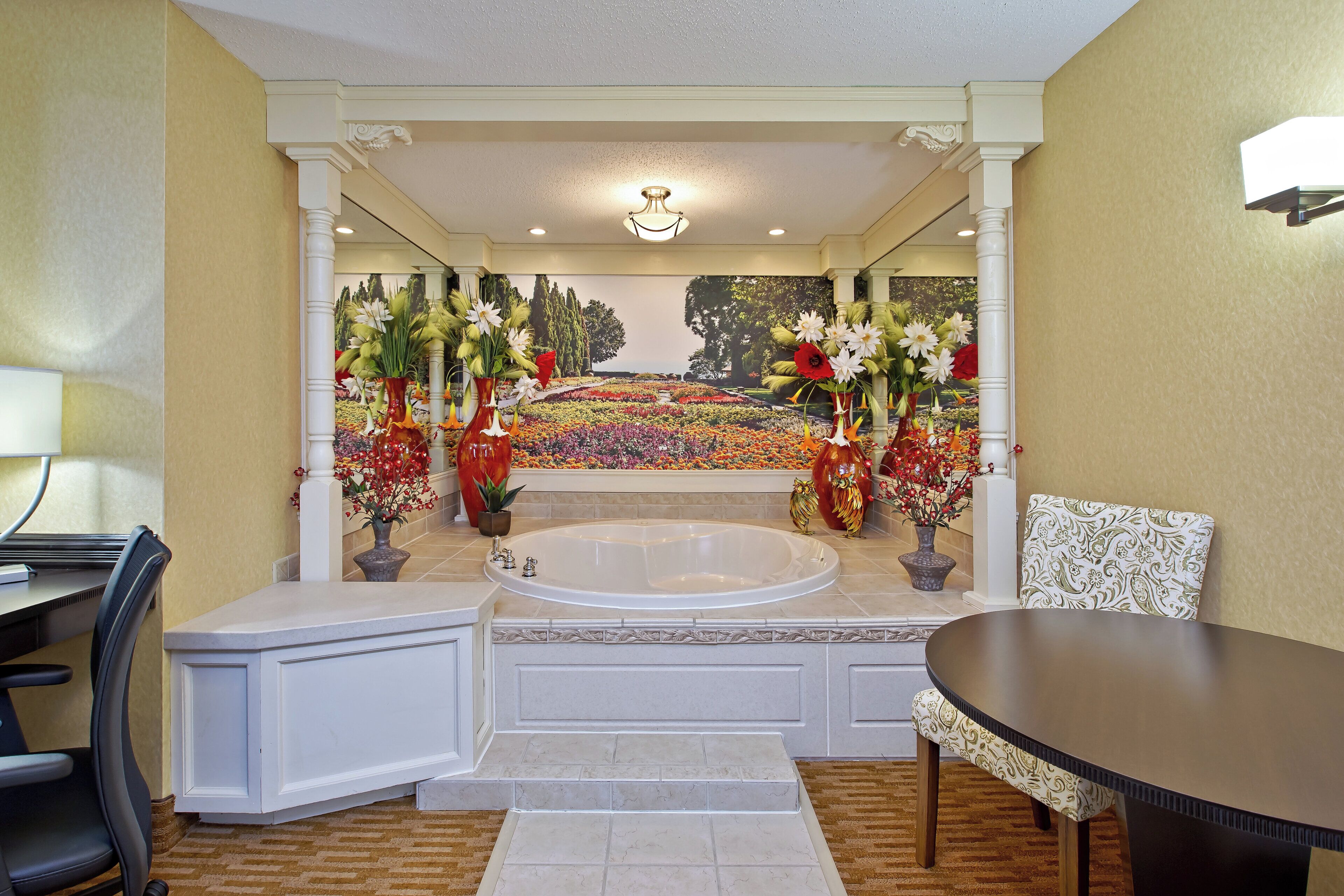A bathroom with a bathtub, a shower area, and a seating area with a table and chairs.