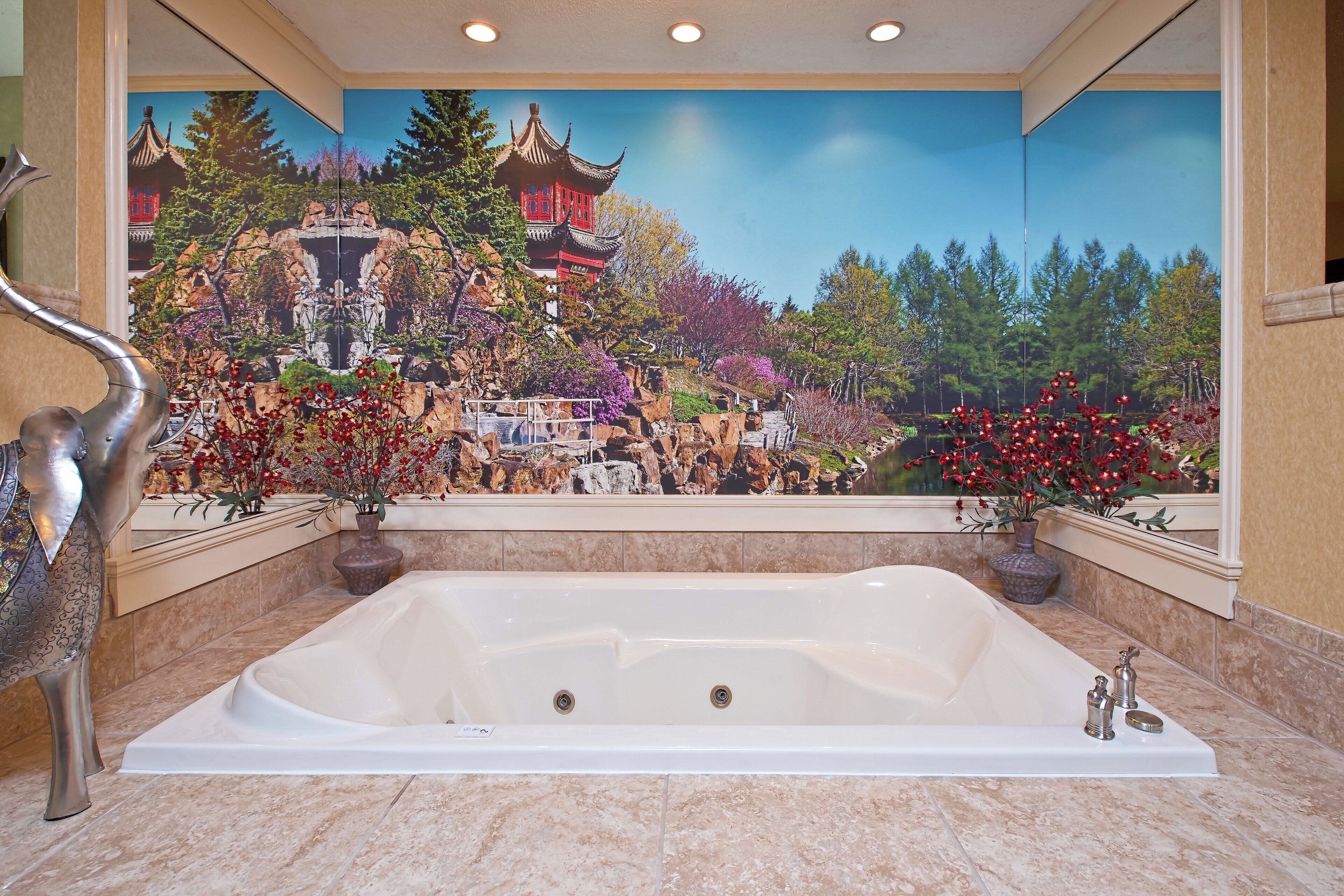 A large, white bathtub in a bathroom with a mural of a traditional Chinese landscape on the wall.