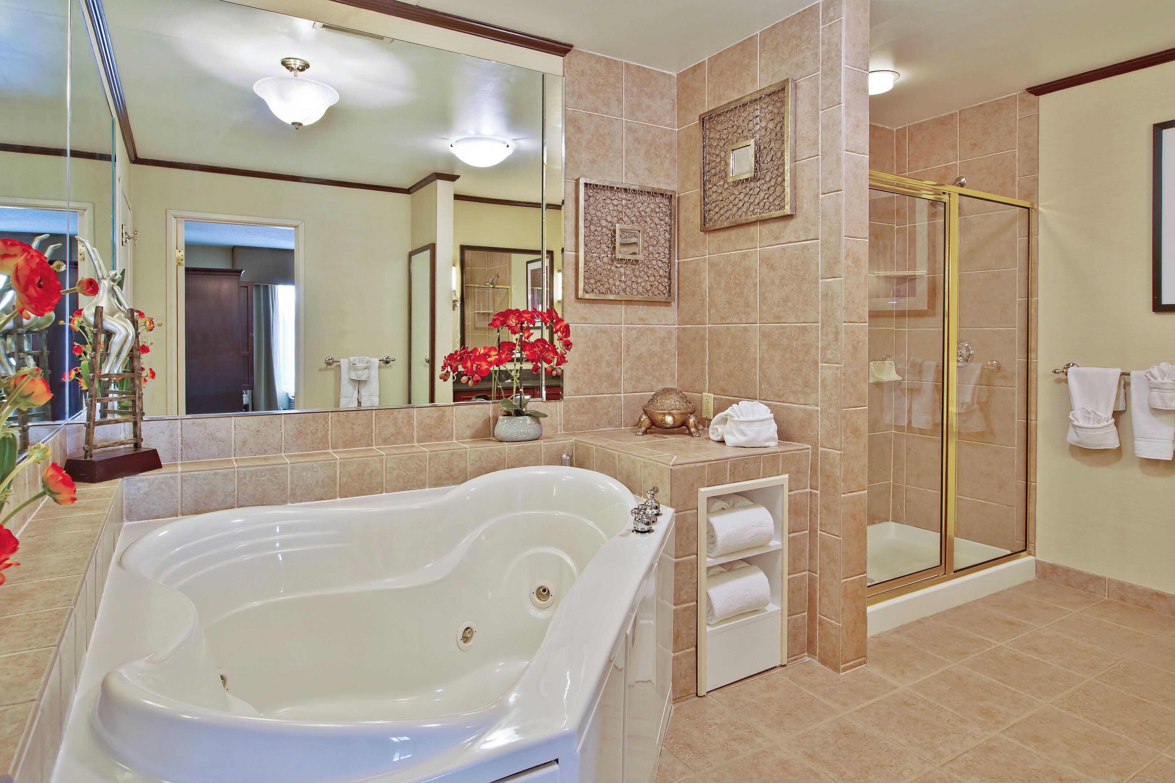 Une salle de bain dotée d’une grande baignoire, d’une douche à parois de verre et d’un meuble-lavabo avec un miroir.
