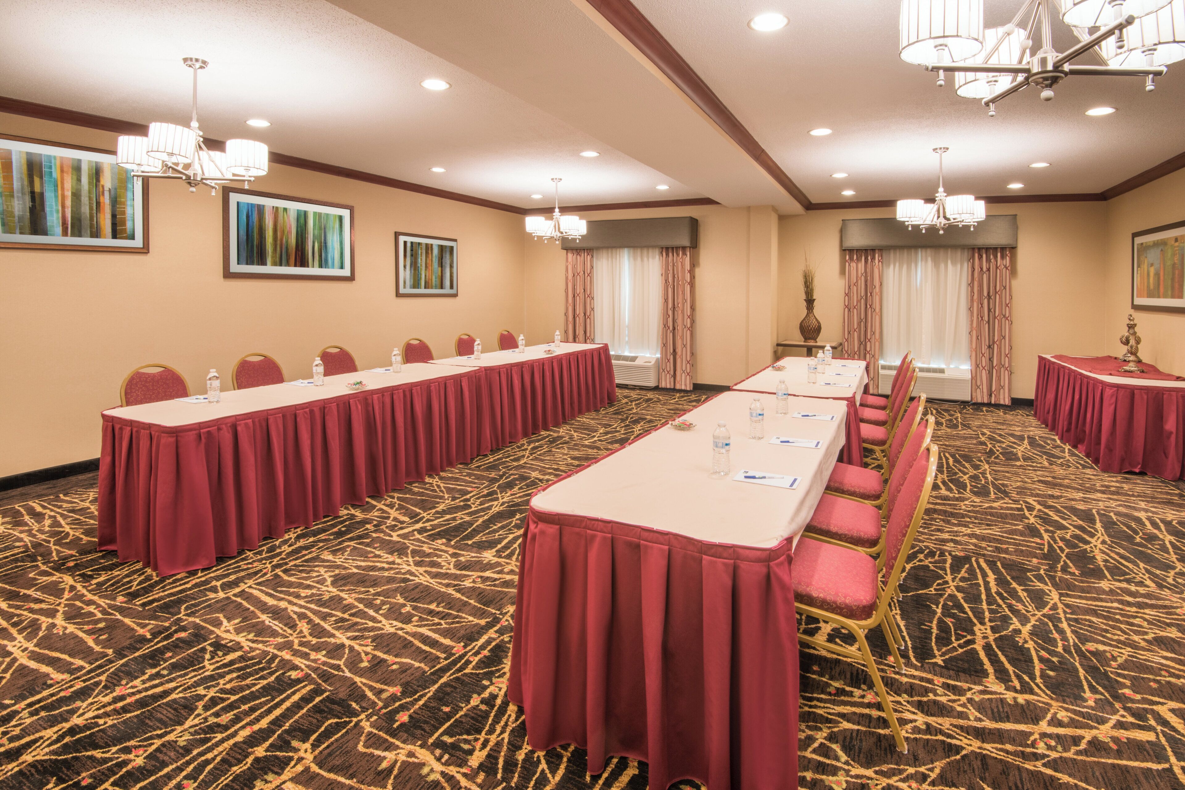 Un salón de conferencias con largas mesas, sillas y piso alfombrado.