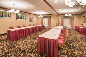 Un salón de conferencias con largas mesas, sillas y piso alfombrado.