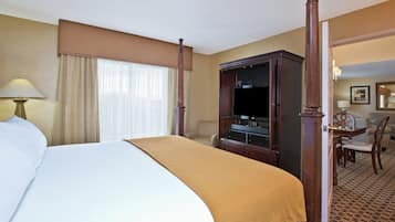 A hotel room with a large bed, a television, a desk with a chair, and a wardrobe.