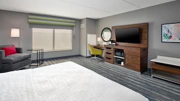 Une chambre d’hôtel avec un grand lit, un bureau avec un ordinateur, une télévision et une chaise.