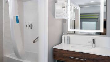 A modern bathroom with a white bathtub, a vanity with a mirror, and a towel rack.