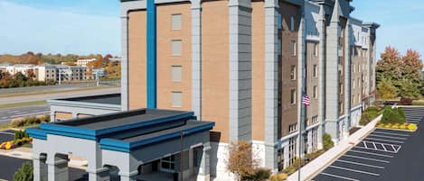 A Hampton Inn & Suites hotel with a modern brick facade, a blue entrance canopy, and a parking lot with marked spaces.