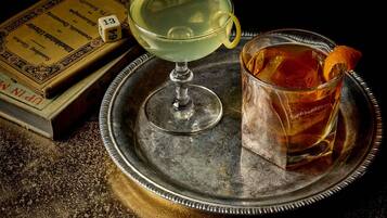 A tray with a cocktail glass and a glass of tea, a book, and a dice.