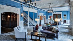 A spacious lobby with a grand staircase, a fireplace, and a seating area with a sofa and armchairs. - Colgate Inn (Hamilton)