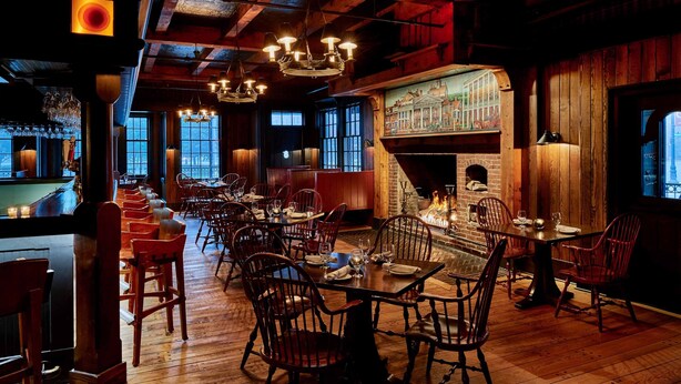A cozy restaurant with wooden interiors, a bar area, and a fireplace. - Colgate Inn (Hamilton)