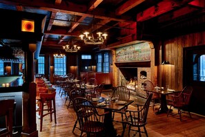 Un restaurante acogedor con interiores de madera, una zona de bar y una chimenea.