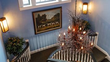 A staircase with white balusters, a chandelier, and a framed painting on the wall.