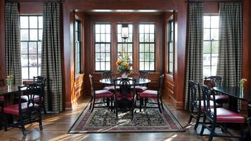 Une salle à manger avec une table ronde, des chaises à coussins rouges et un arrangement floral en guise de décoration centrale.