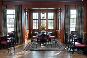 A dining room with a round table, red cushioned chairs, and a floral centerpiece.