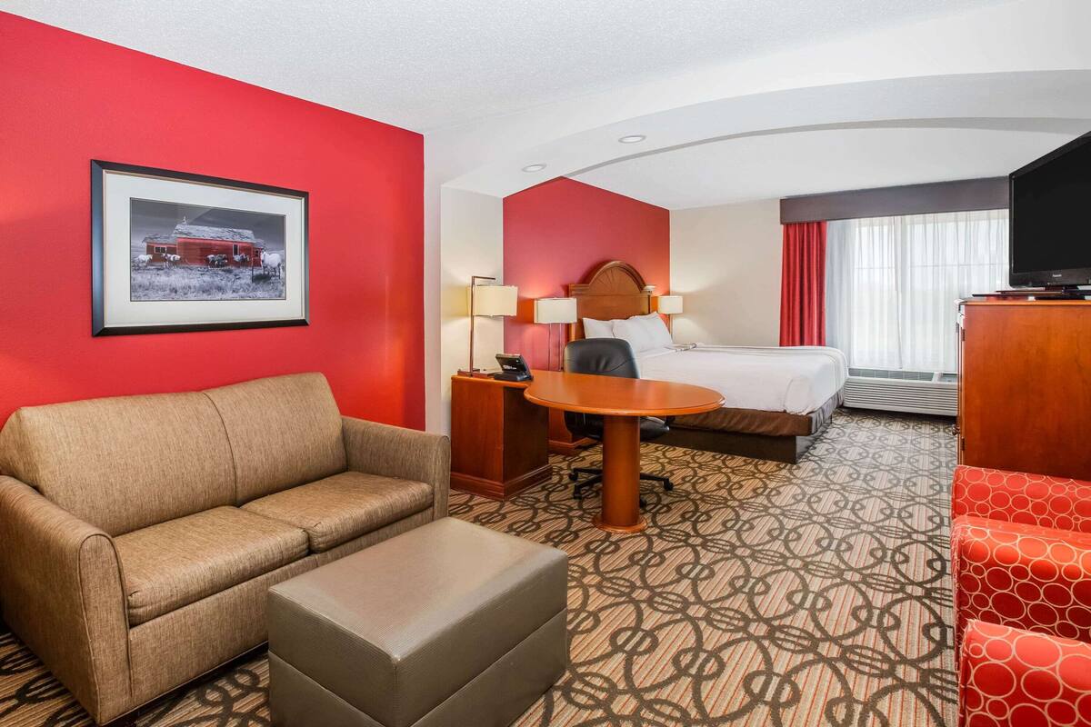 Ein Hotelzimmer mit Bett, Schreibtisch, Sofa und Fernseher.