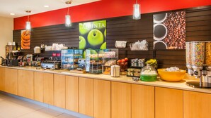 Una estación de café con pared roja y negra, un letrero que dice "LA QUINTA", y diferentes productos de café y comida.