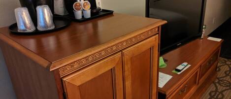 Un mueble de madera con una cafetera y dos cápsulas de café encima.