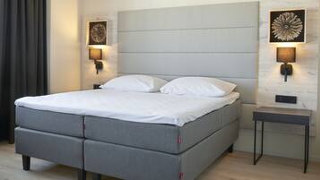 A modern bedroom with a grey sofa bed, two wall-mounted lamps, and a small table.