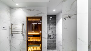 A modern bathroom with a wooden sauna, a shower, and marble walls.