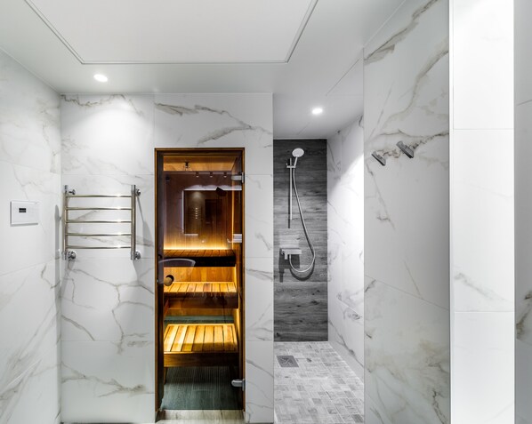 Une salle de bain moderne avec un sauna en bois, une douche et des murs en marbre.