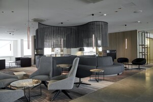 Een moderne lounge met grijze banken, een gebogen zithoek en een decoratieve wand.