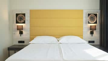 Un lit double avec une tête de lit en bois, deux tables de chevet et des lampes fixées au mur.