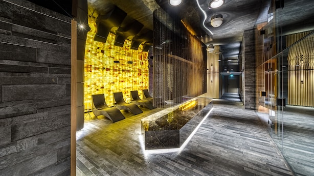 A modern lobby with a reception desk, seating area, and a patterned wall.
