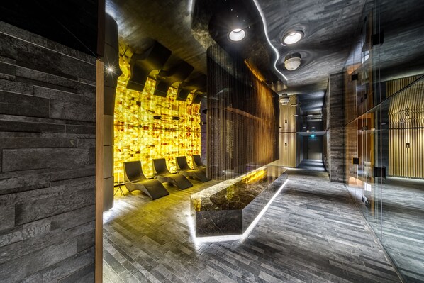 Een moderne lobby met een receptiebalie, een zithoek en een behang met een patroon.