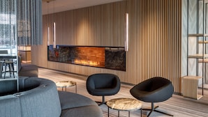 A modern interior with a fireplace, dark sofas, and a wooden wall.