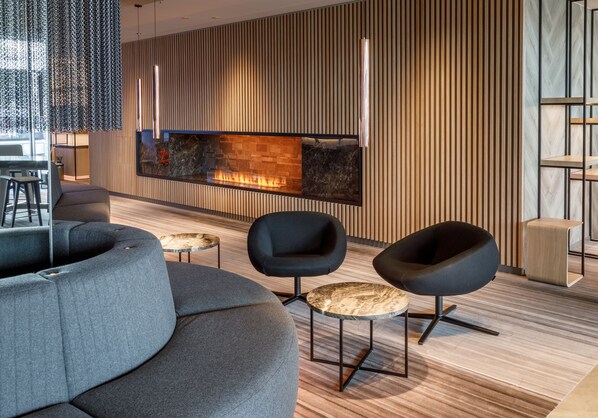 Un intérieur moderne avec une cheminée, des canapés sombres et un mur en bois.