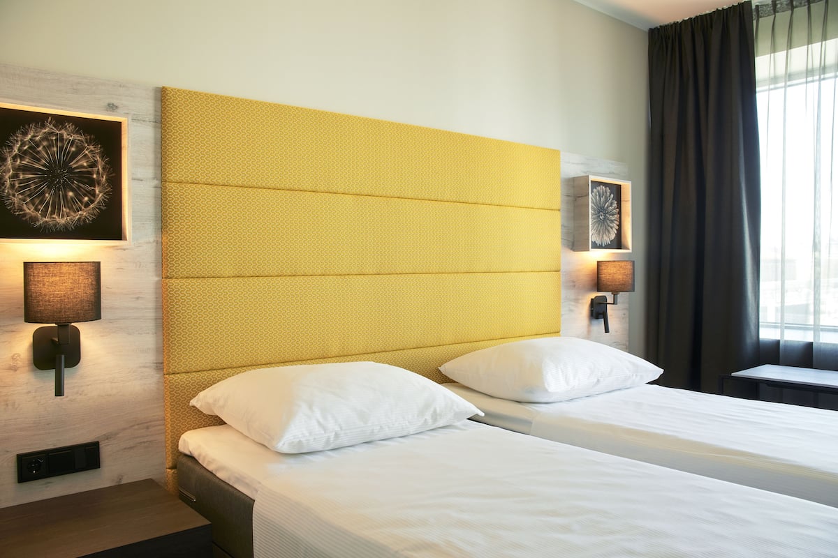 Een hotelkamer met een groot bed, twee bedlampjes en een kunstwerk aan de muur.