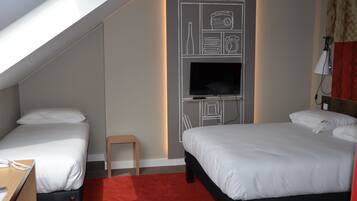 Une chambre d’hôtel avec deux lits, une télévision, une petite table et une moquette rouge.