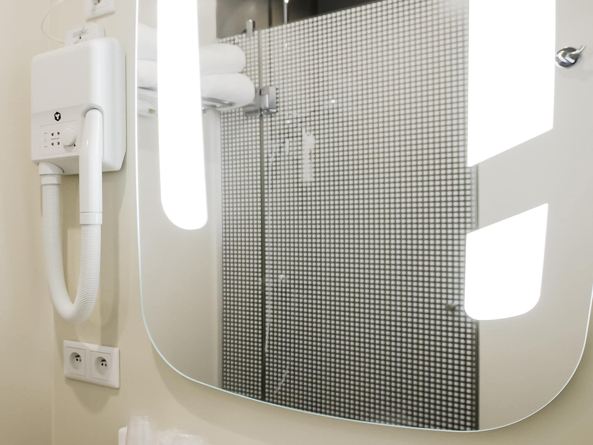 A bathroom with a white sink, a mirror, and a tiled wall.