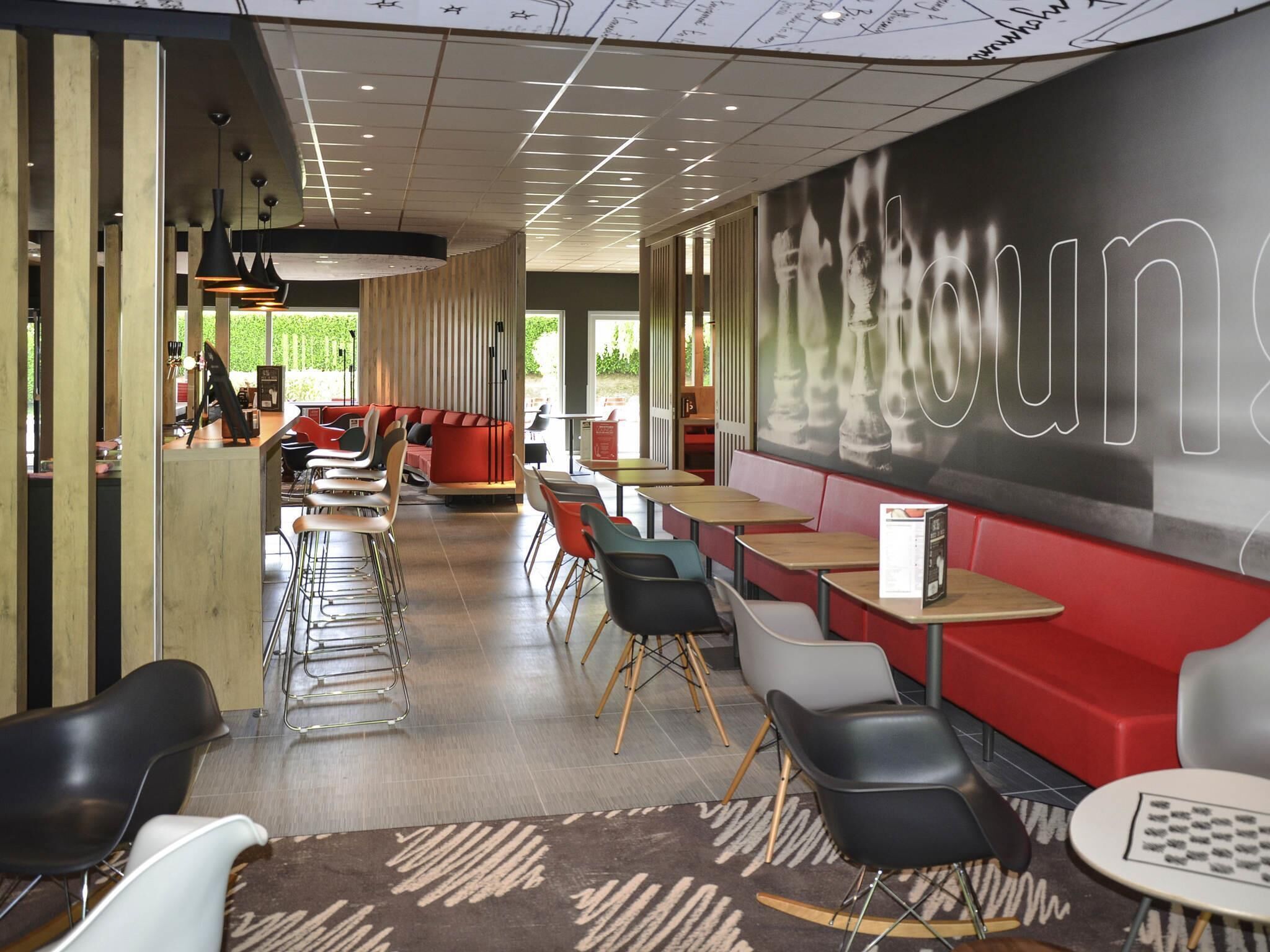 A modern cafe with a long counter, red seating, and a large mural.