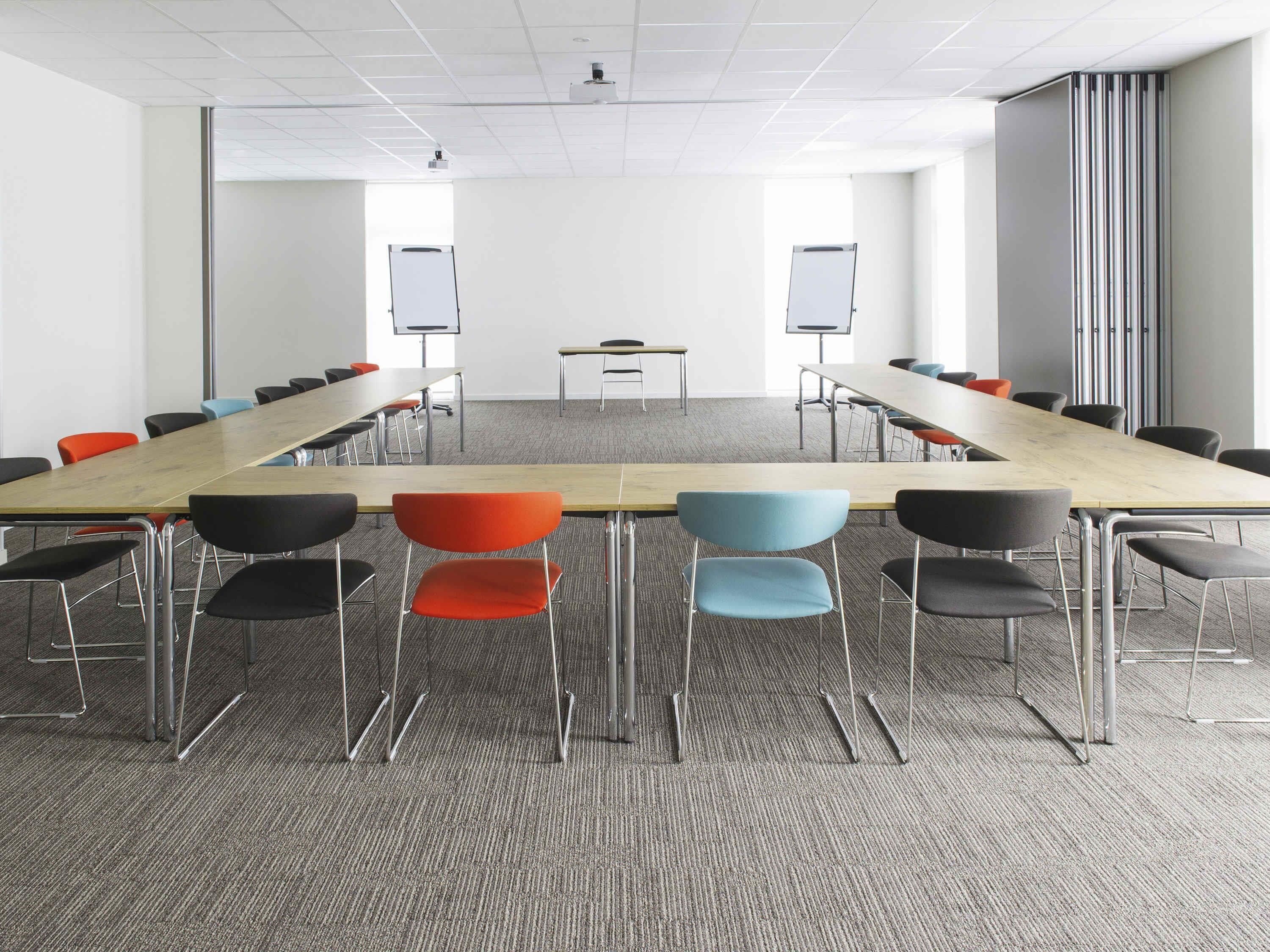 Une salle de conférence équipée d’une longue table, de nombreuses chaises, de tableaux blancs et d’un projecteur.