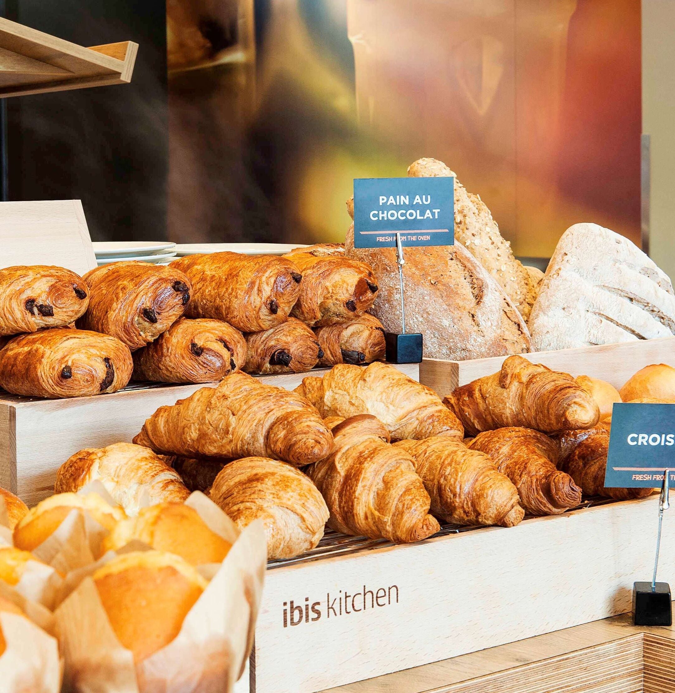A bakery display with various types of bread and pastries, including croissants and pain au chocolat.