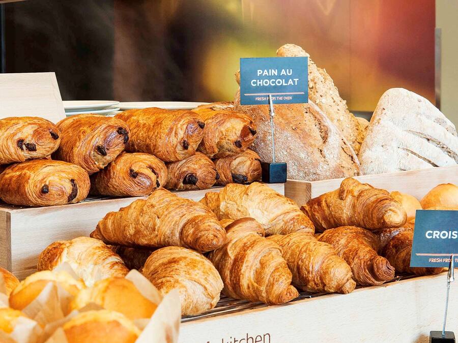 A bakery display with various types of bread and pastries, including croissants and pain au chocolat.