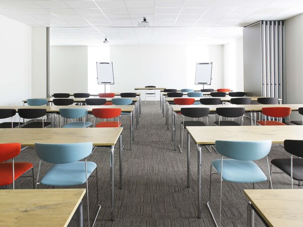 A classroom with rows of desks and chairs, a projector, and a whiteboard. - ibis Wavre Brussels East (Wavre)